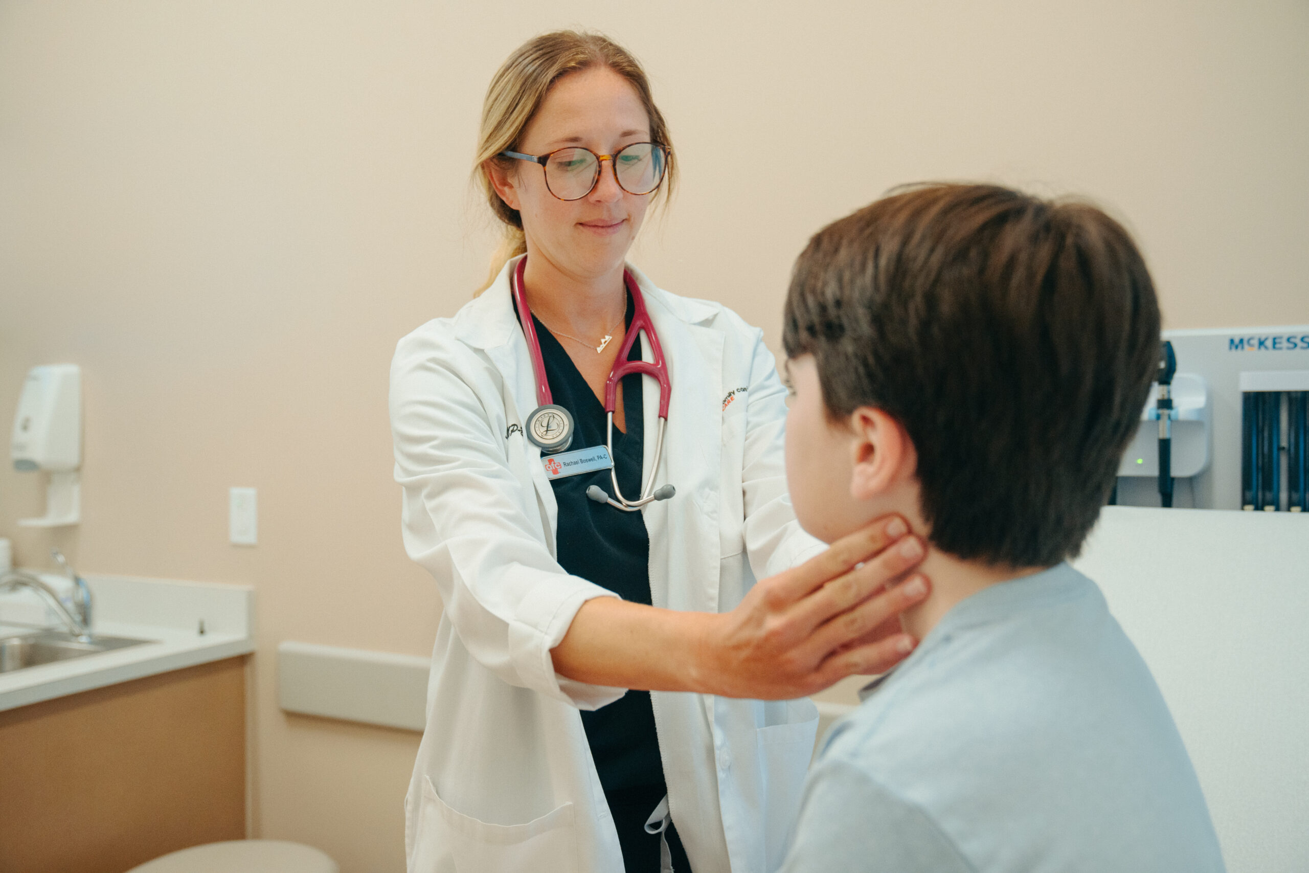 Female AFC provider checks patient's lymph nodes for RSV