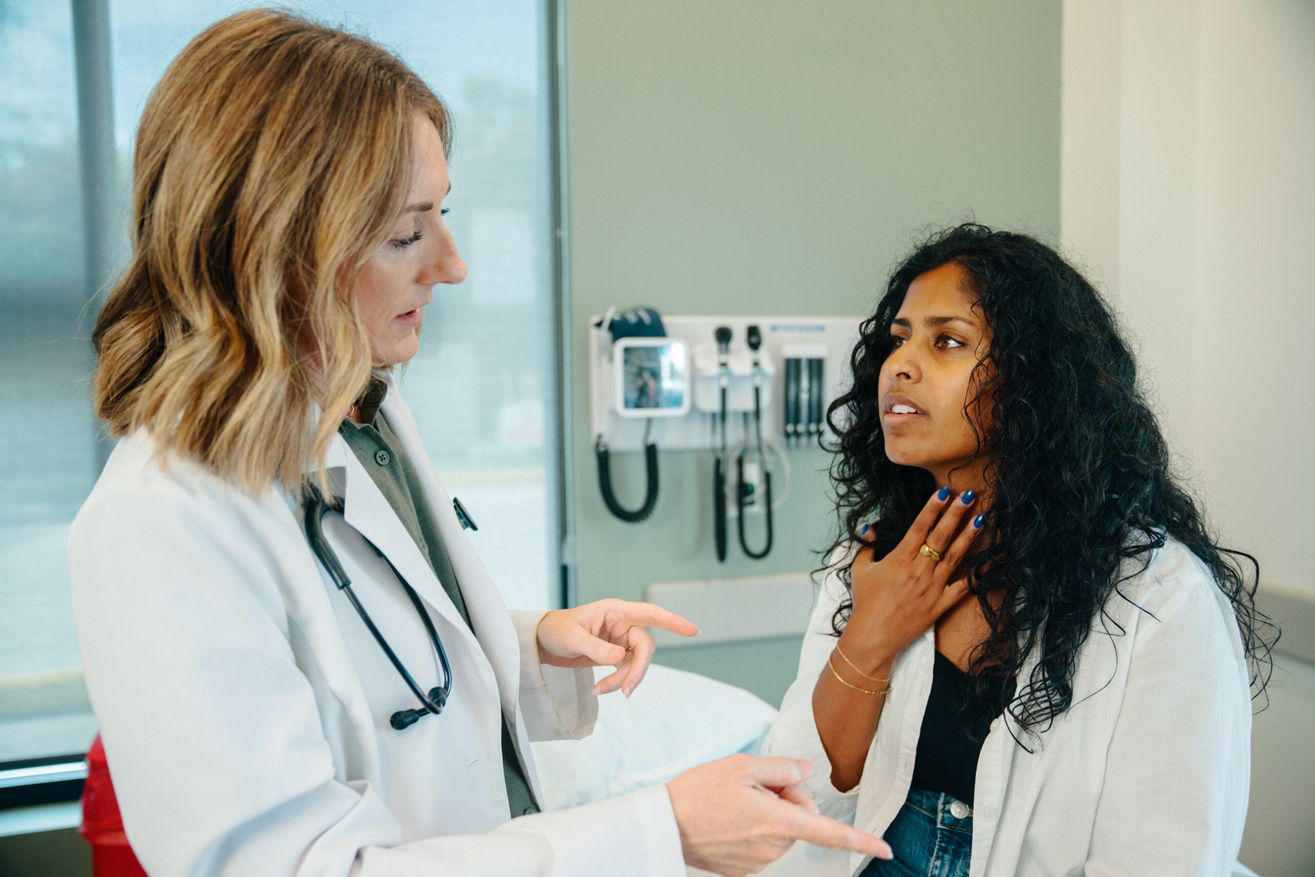 Female patient points to sore throat with AFC provider examining for strep